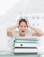 Angry businesswoman shouting with stack of folders at desk