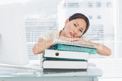 Bored businesswoman with stack of folders at desk