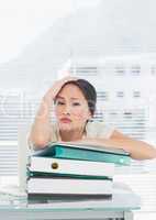 Bored businesswoman with stack of folders at desk