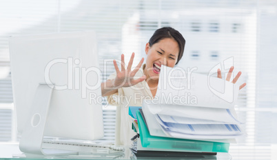 Businesswoman shouting with stack of folders at desk
