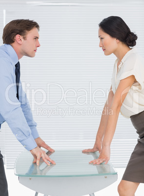 Business couple looking at each other with palms at desk
