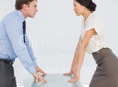 Business couple looking at each other with palms at desk