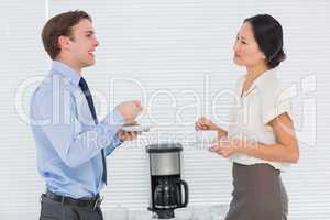 Business couple with tea cups chatting in office