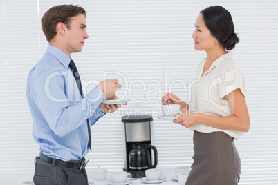 Business couple with tea cups chatting in office