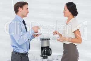 Business couple with tea cups chatting in office