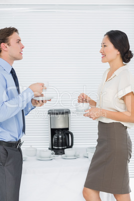 Business couple with tea cups chatting in office