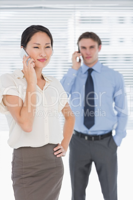 Businesswoman and man using cellphones in office