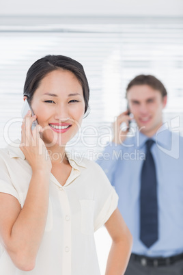 Businesswoman and man using cellphones in office