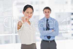 Businesswoman pointing towards camera with man in office