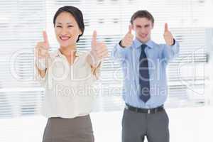 Business colleagues gesturing thumbs up in office