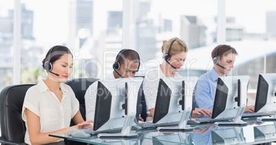 Colleagues with headsets using computers at desk