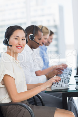 Business colleagues with headsets using computers at desk