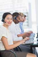 Business colleagues with headsets using computers at desk