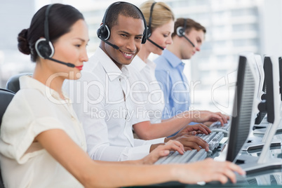 Business colleagues with headsets using computers at desk