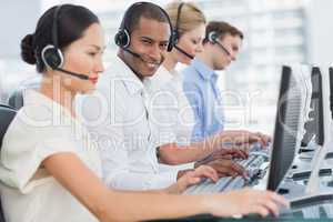 Business colleagues with headsets using computers at desk