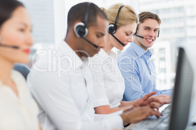 Business colleagues with headsets using computers at desk