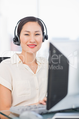 Female executive with headset using computer at desk