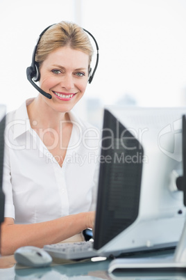 Female executive with headset using computer at desk