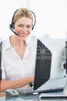 Female executive with headset using computer at desk