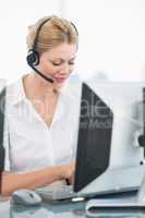 Female executive with headset using computer at desk