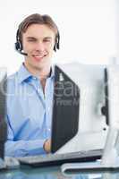 Male executive with headset using computer at desk