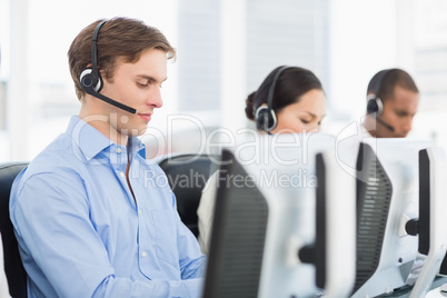 Business colleagues with headsets using computers in office