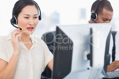 Colleagues with headsets using computers at office