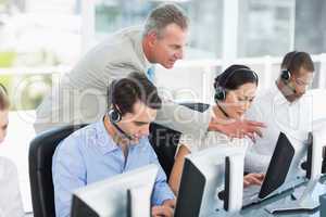 Manager looking at executives with headsets using computers