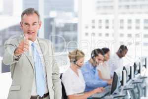Businessman gesturing thumbs up with executives using computers