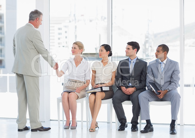 Businessman shaking hands with woman by people waiting for inter