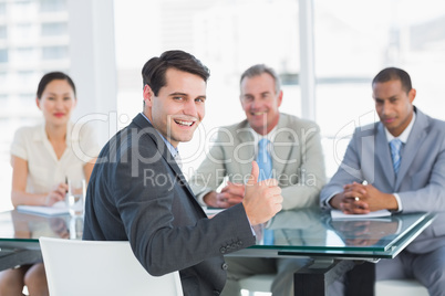 Executive gesturing thumbs up with recruiters during job intervi