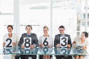 Group of panel judges holding score signs