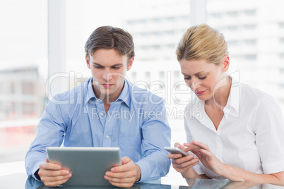 Businessman and woman using digital tablet and cellphone at offi