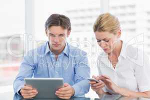 Businessman and woman using digital tablet and cellphone at offi