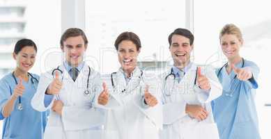 Cheerful doctors gesturing thumbs up at hospital