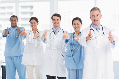Confident doctors gesturing thumbs up at hospital