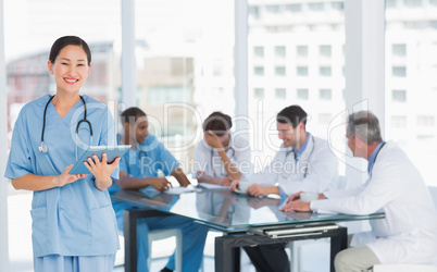 Surgeon using digital tablet with group around table in hospital