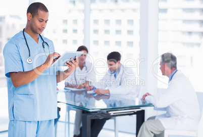 Surgeon using digital tablet with group around table in hospital