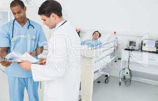 Doctors looking at reports with patient in hospital