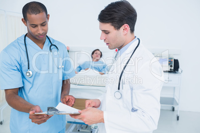 Doctors looking at reports with patient in hospital