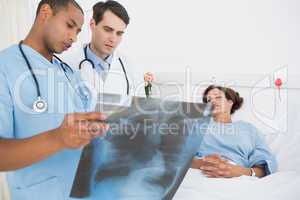 Doctors examining x-ray by patient in hospital
