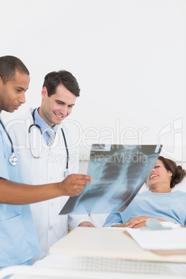 Doctors examining x-ray by patient in hospital