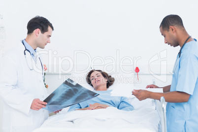 Doctors examining x-ray by patient in hospital