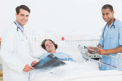 Doctors with x-ray by female patient in hospital