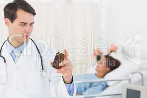 Doctor holding a bottle of pills with patient in hospital