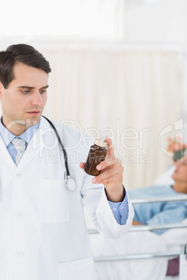 Doctor holding a bottle of pills with patient in hospital