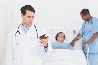 Doctor holding a bottle of pills with patient in hospital