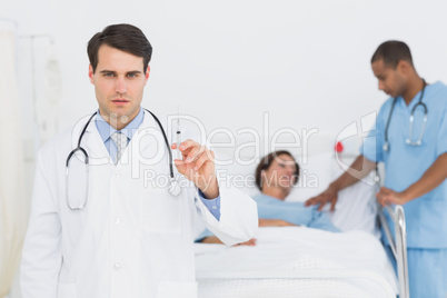 Doctor holding a syringe with patient in hospital