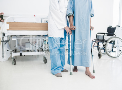 Doctor helping patient in crutches at the hospital