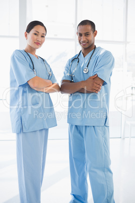 Confident surgeons with arms crossed in hospital